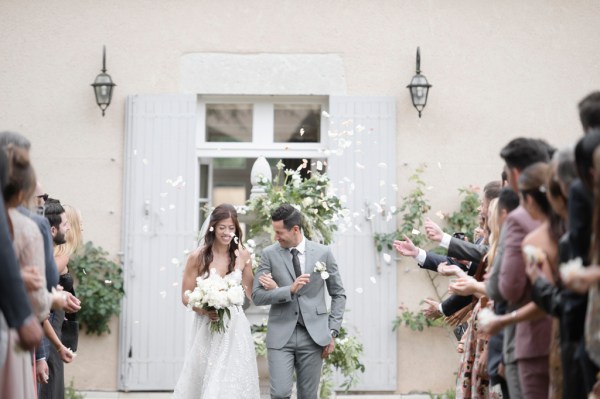 Bride and groom exit ceremony confetti is being thrown on couple by guests