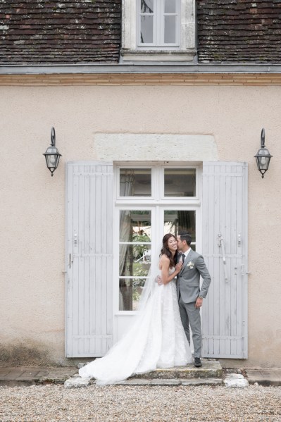 Bride and groom stand beside wedding venue entrance kiss on the cheek