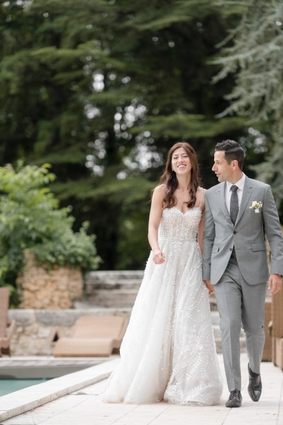 Bride and groom walk together holding hands in garden