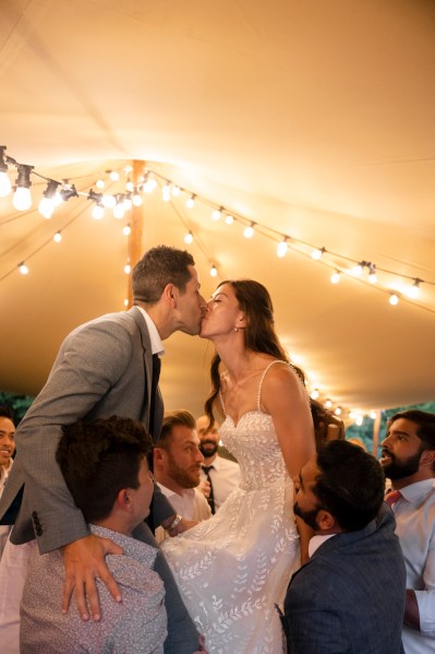 Bride and groom are on guests shoulders they kiss each other