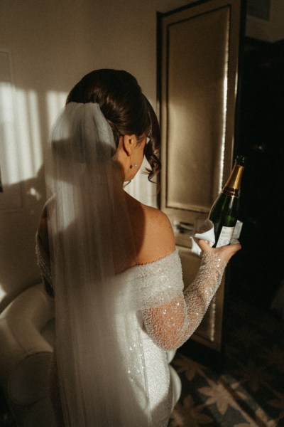 Dark photo of bride holding wine champagne bottle