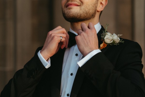 Close up of grooms suit getting ready bowtie