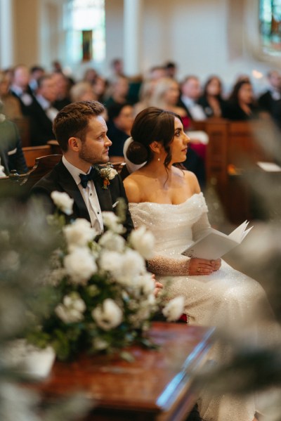 White flowers roses bride and groom sit during ceremony church