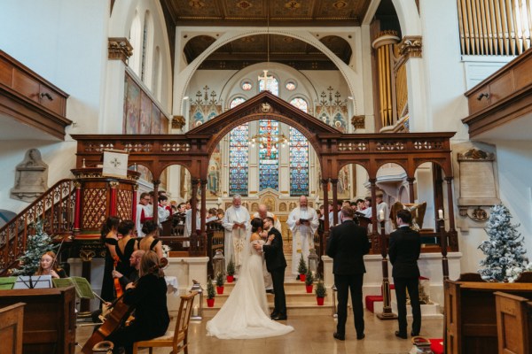 Guests clap bride and groom kiss at the alter