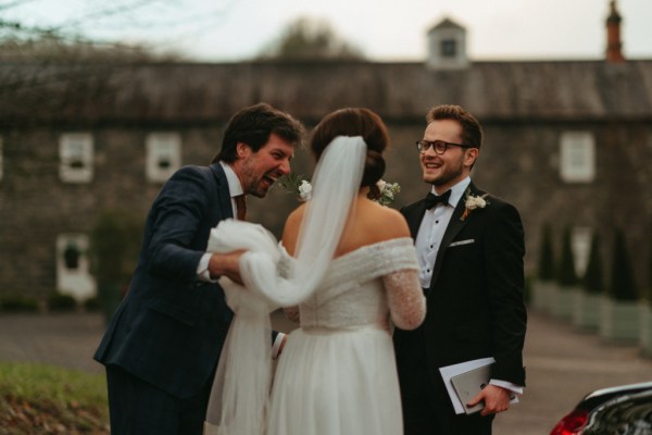 Bride groom and friend holds her veil