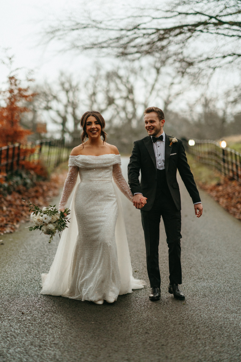 Pathway shot of bride and groom hand in hand smiling