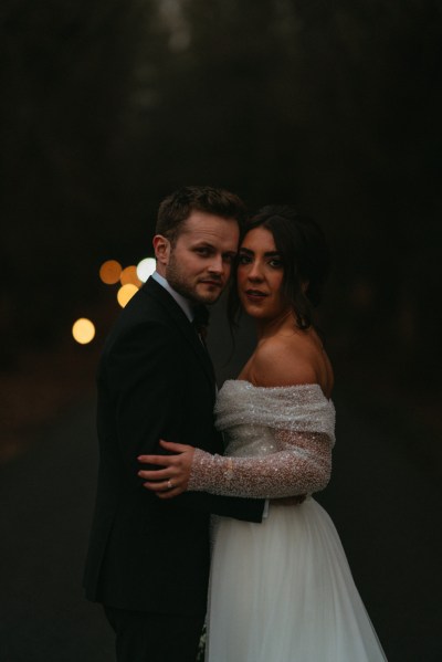 Dark shot of bride and groom hugging in forest