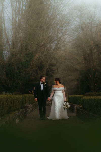 Bride and groom moody shot holding hands in garden