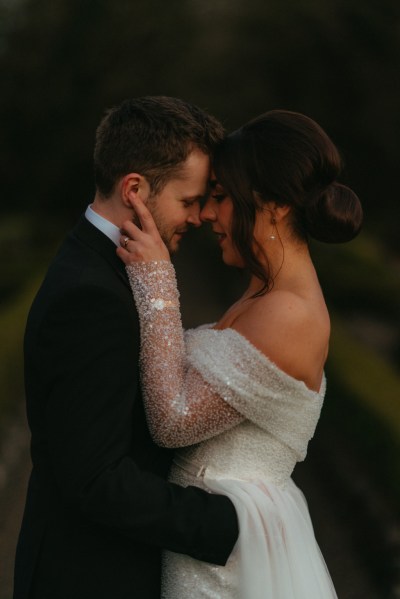 Dark moody shot of bride and groom smiling hugging embracing