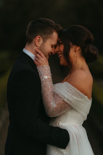 Dark moody shot of bride and groom smiling hugging embracing