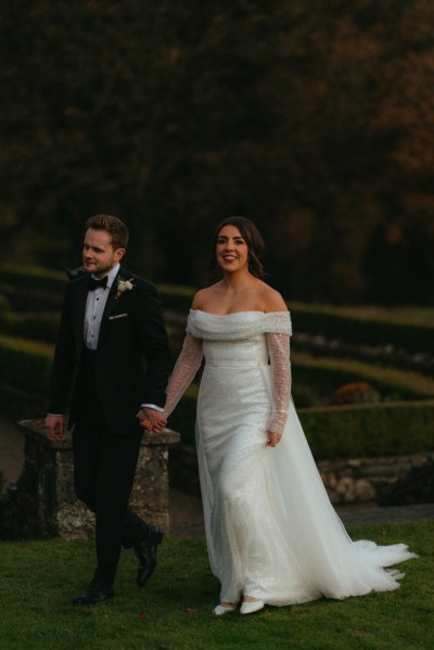 Bride and groom are hand in hand walking in garden