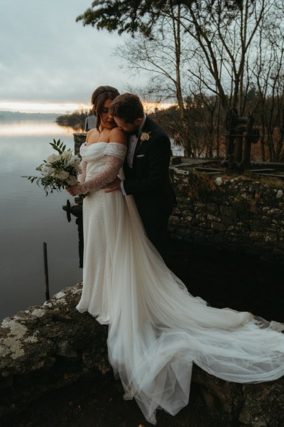 Moody evening shot of bride and groom edge of cliff lake landscape water