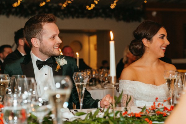 Bride and groom sitting at dining table candles lit