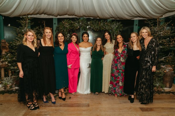 Bride and her female friends pose inside of marquee tent portrait