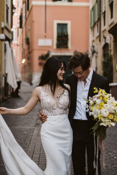 Bride and groom walk down street she holds bouquet flowers