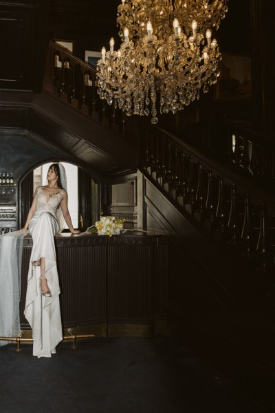 Dark image of bride sitting long train and veil interior chandelier