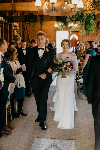 Father of the bride walks down the aisle surrounded by guests