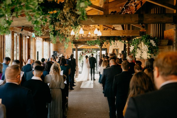 Bride and groom at the top of alter with celebrant shot of guests standing