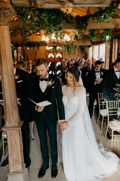 Bride and groom at top of alter reading from booklet in front of guests