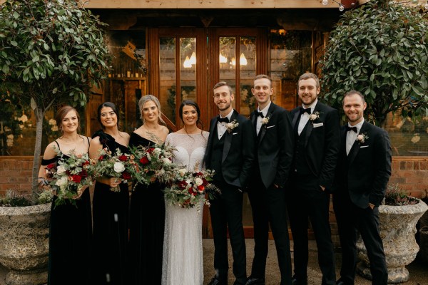 Bride groom groomsmen groom best man pose for a picture outside wedding venue