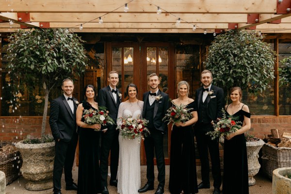 Bride groom groomsmen groom best man pose for a picture outside wedding venue