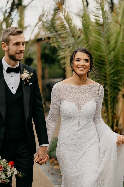 Bride and groom hold hands smiling