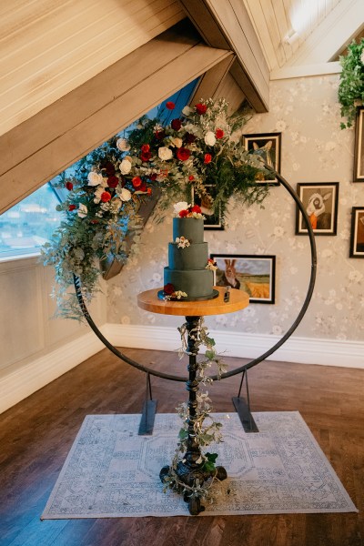 Close up of black charcoal wedding cake covered in flowers sitting on table circular flower bed