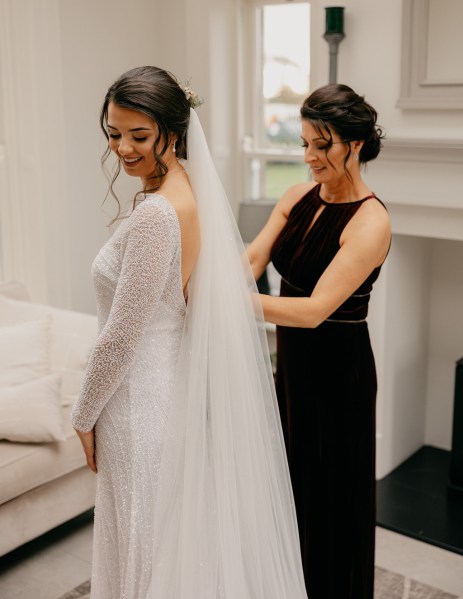 Bridesmaid helps bride get ready before wedding ceremony