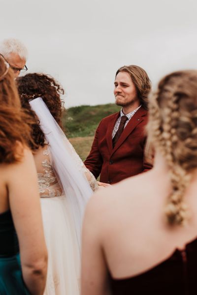 bride and groom smile during ceremony with bridesmaids beside them