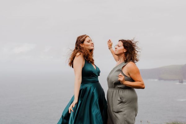 Bridesmaids dancing celebrating on edge of cliff wind Irish landscape setting