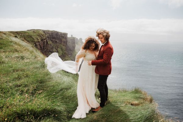 Bride and groom veil in the air Clare setting sea on the top of a cliff Irish landscape