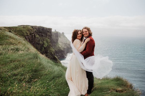 Bride and groom veil in the air Clare setting sea on the top of a cliff Irish landscape