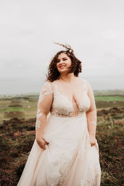 Bride poses on cliff in bridal gown dress