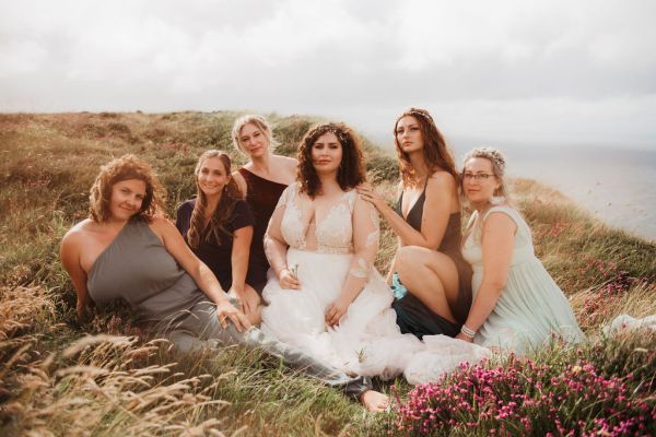 Bride bridesmaids sitting on edge of cliff Irish setting landscape