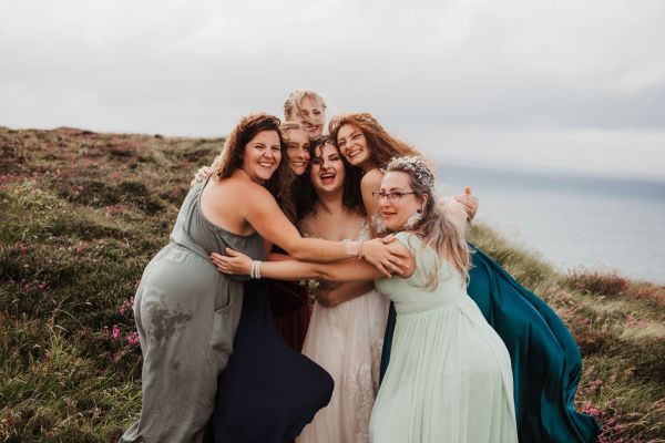 Bride bridesmaids standing on edge of cliff Irish setting landscape