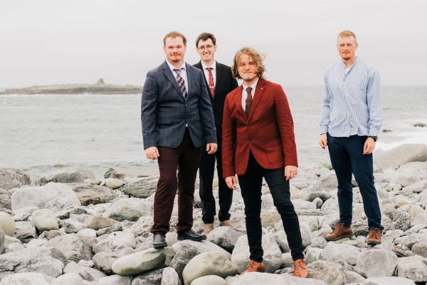 Groom and his groomsmen pose on the rocks beach setting