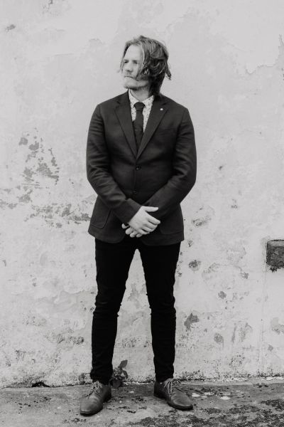 Black and white image of groom standing on his own exterior shot