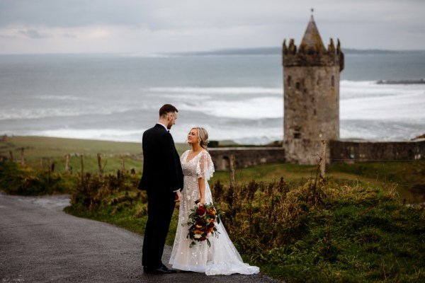 Castle setting bride and groom near farm park setting standing on the road