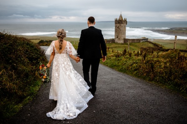 Castle setting bride and groom near farm park setting standing on the road they walk hand in hand