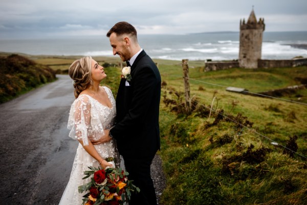 Castle setting bride and groom near farm park setting standing on the road looking at each other