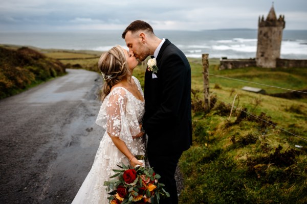 Castle setting bride and groom near farm park setting standing on the road kissing kiss