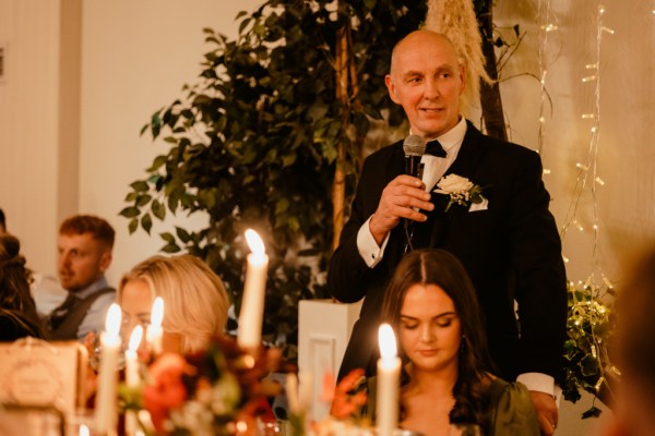 Father gives speech as he speaks into microphone to guests