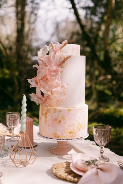 Pink cake on table candles forest setting