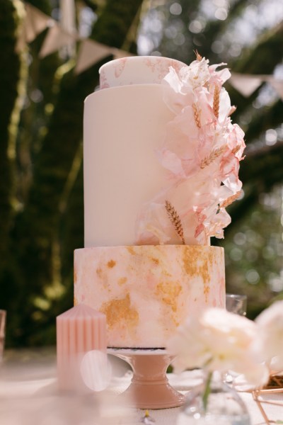 Pink cake on table candles forest setting