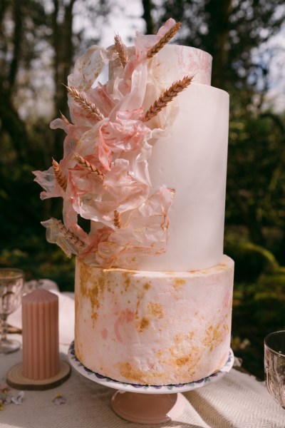 Pink cake on table candles forest setting