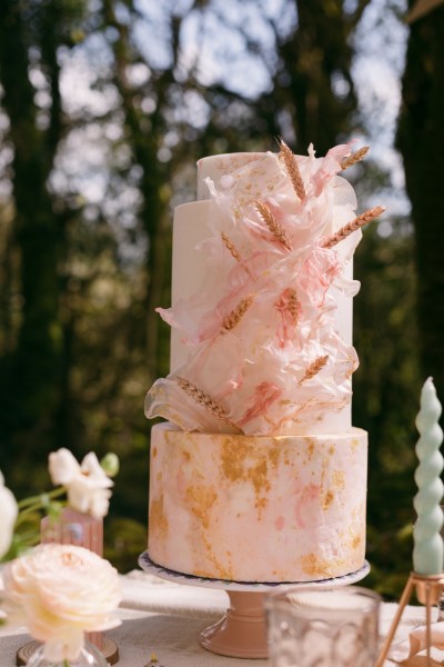 Pink cake on table candles forest setting