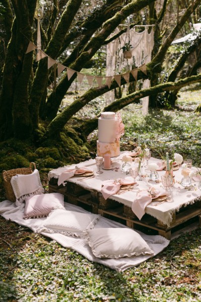 Pink cake on table candles forest setting trees banner