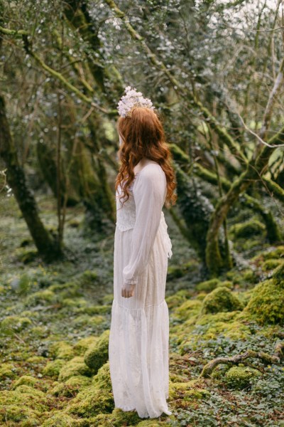 Model bride close up red head wearing floral flower headband in forest setting looking away