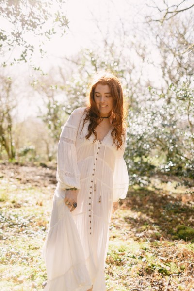 Model bride swings around dances in forest setting trees sun is shining down