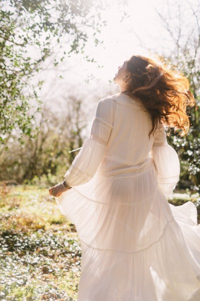 Model bride swings around dances in forest setting trees